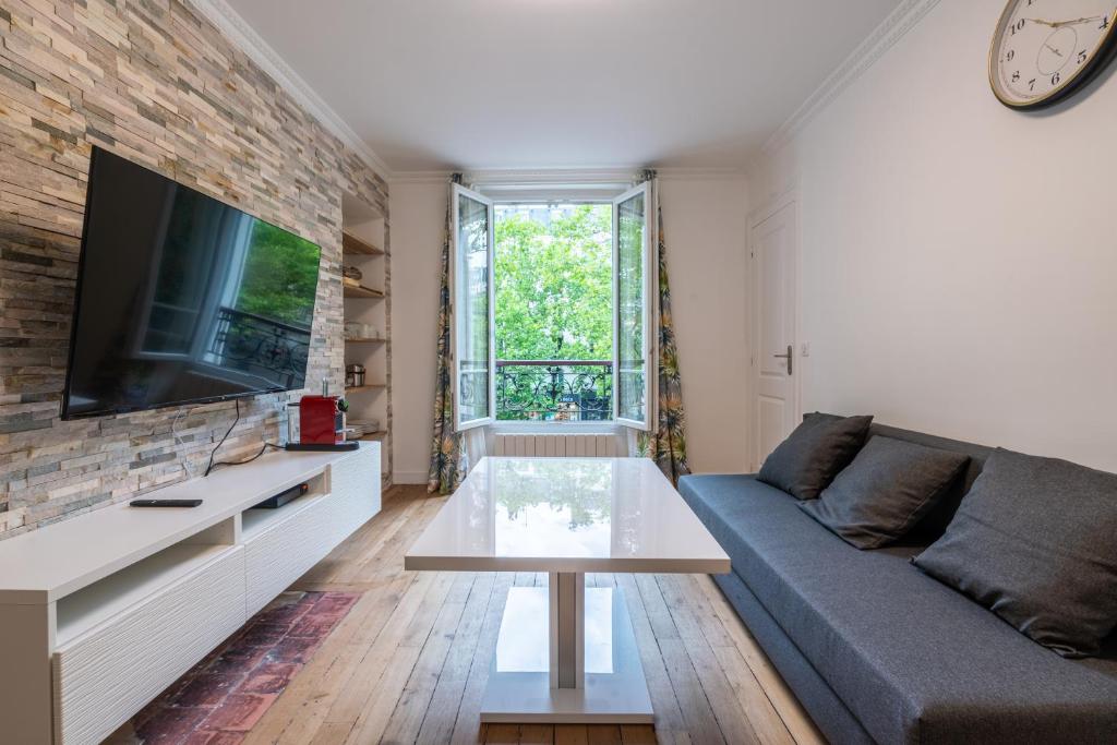 a living room with a couch and a tv at logement cosy et moderne proche de toute commodité in Paris