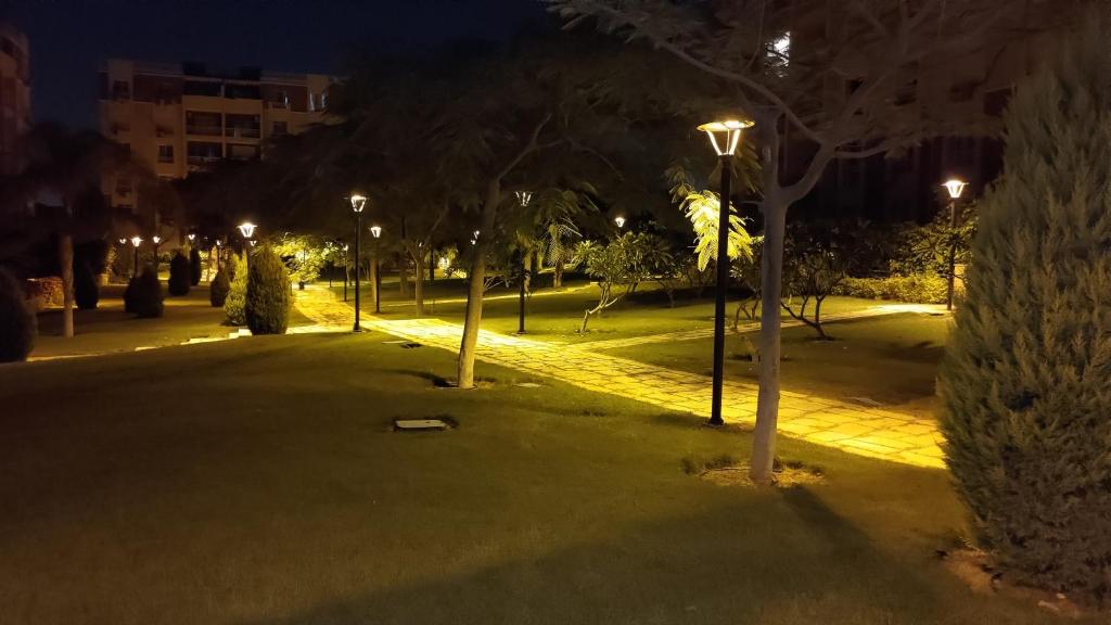 a park at night with trees and street lights at Lovely 2-bedrooms Apartment with free parking in Madīnat ash Shurūq