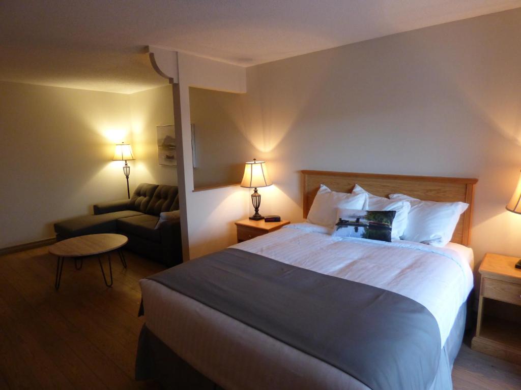 a hotel room with a bed and a couch at Château Logue Hotel in Maniwaki