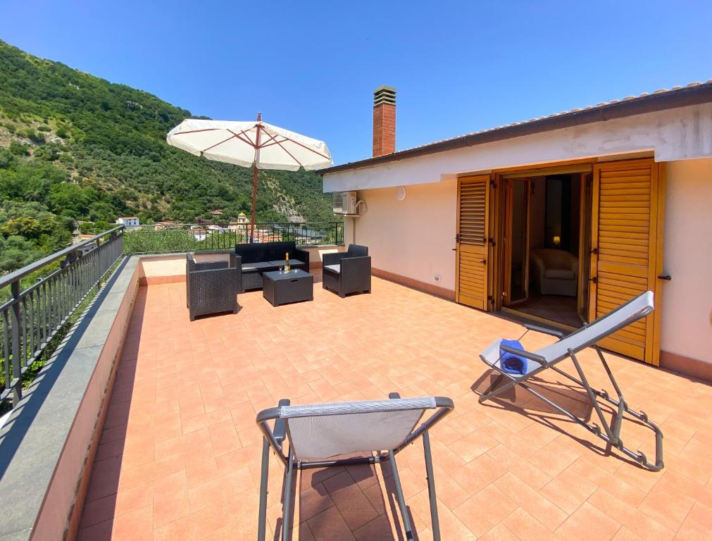 un patio con sillas y una sombrilla en el balcón en Arya's House, en Colli di Fontanelle