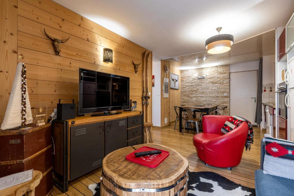 a living room with a red chair and a television at APPARTEMENT CENTRE VILLE PARKING COUVERT WIFI BALCON in Cauterets