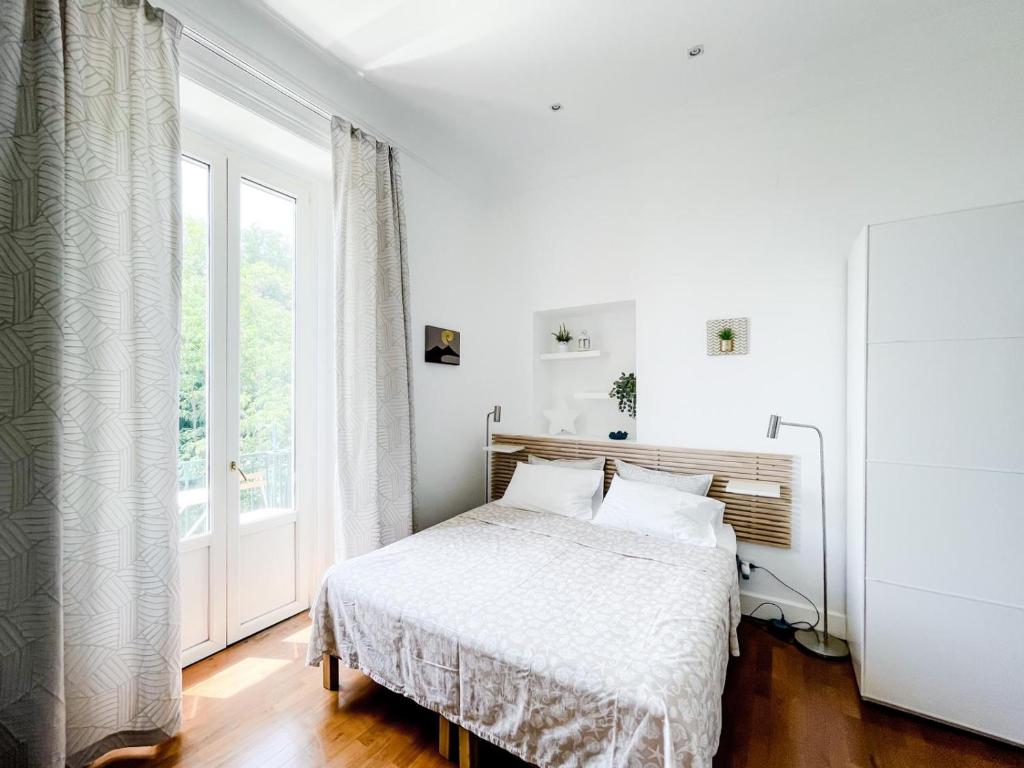 a white bedroom with a bed and a window at I Love Mergellina in Naples