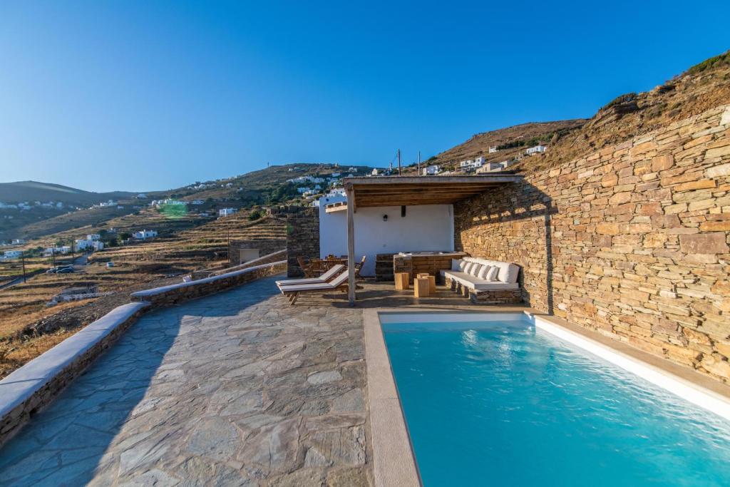 a swimming pool in front of a building with a stone wall at villaV in Triandáros