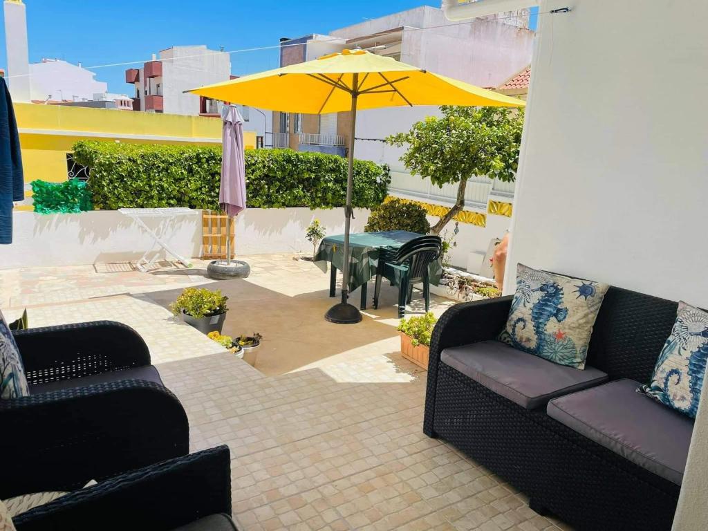 d'une terrasse avec deux canapés et un parasol jaune. dans l'établissement Casa da Avo, à Portimão