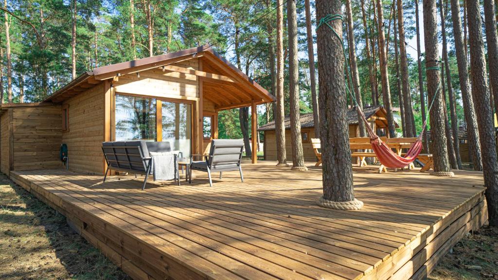 a wooden deck with a house and a playground at Słoneczny Domek Borsk nr 2 i 15 in Borsk