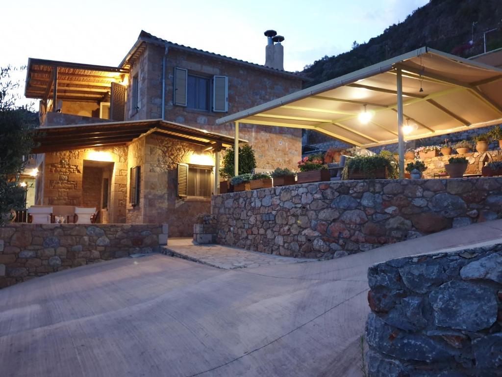 a house with a stone wall and an umbrella at Riza Apartments in Kardamili