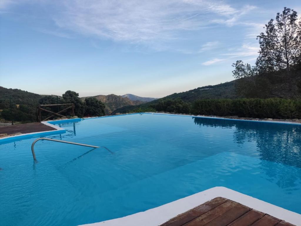 una gran piscina de agua azul con montañas al fondo en Hotel Apartamento Nueva Alcazaba, en Busquístar