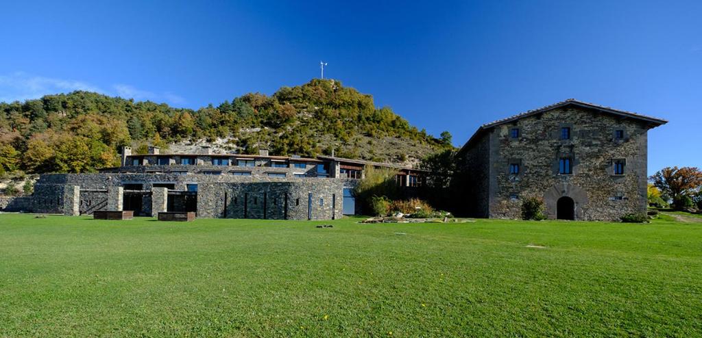 un gran edificio de piedra en un campo de césped verde en L'Avenc Benestar Rural, en Tavertet