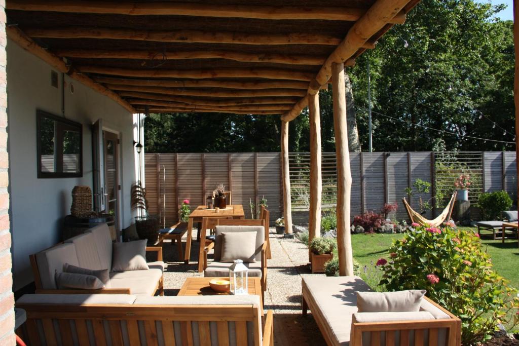 een patio met een houten pergola bij Maison Bellefleur B&B - Pension in Renesse