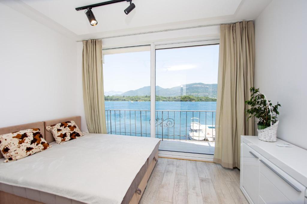 a bedroom with a bed and a large window at Aquamarine House in Tivat