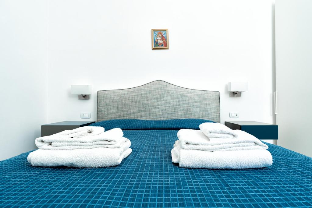 una camera da letto con un letto blu e asciugamani bianchi di La Finestra sul Corso ad Amalfi