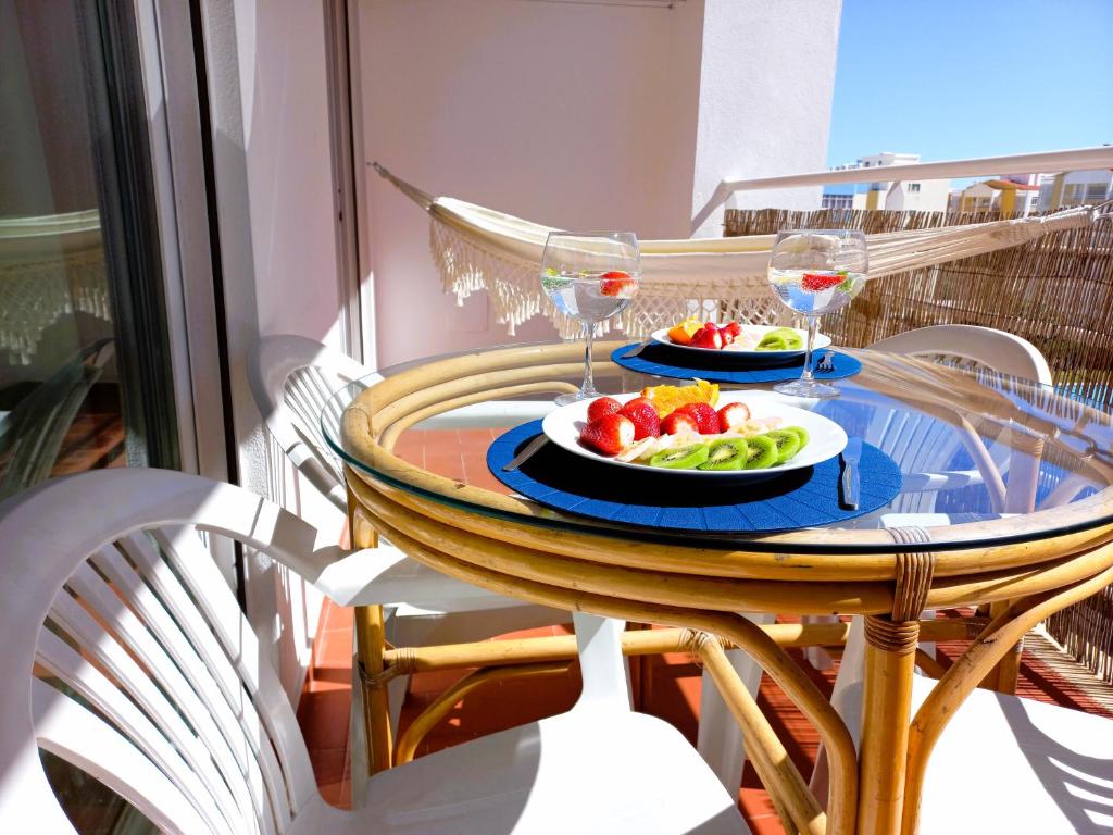 uma mesa com dois pratos de frutas e taças de vinho em Nelo's Cousy place em Portimão