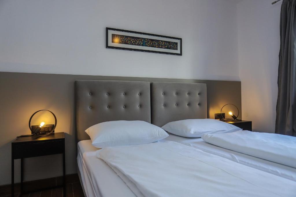 1 Schlafzimmer mit 2 Betten mit weißer Bettwäsche und 2 Lampen in der Unterkunft Apartments Silvano in Poreč
