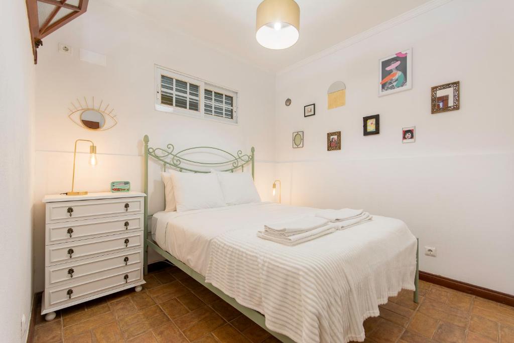 a white bedroom with a bed and a dresser at Casa das Tulipas - Vila Nogueira de Azeitão in Villa Nogueira