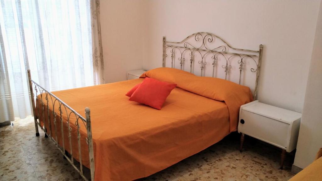 ein Bett mit einer orangefarbenen Tagesdecke und einem roten Kissen in der Unterkunft Appartamento Graziella, nel cuore di Ischia Porto in Ischia
