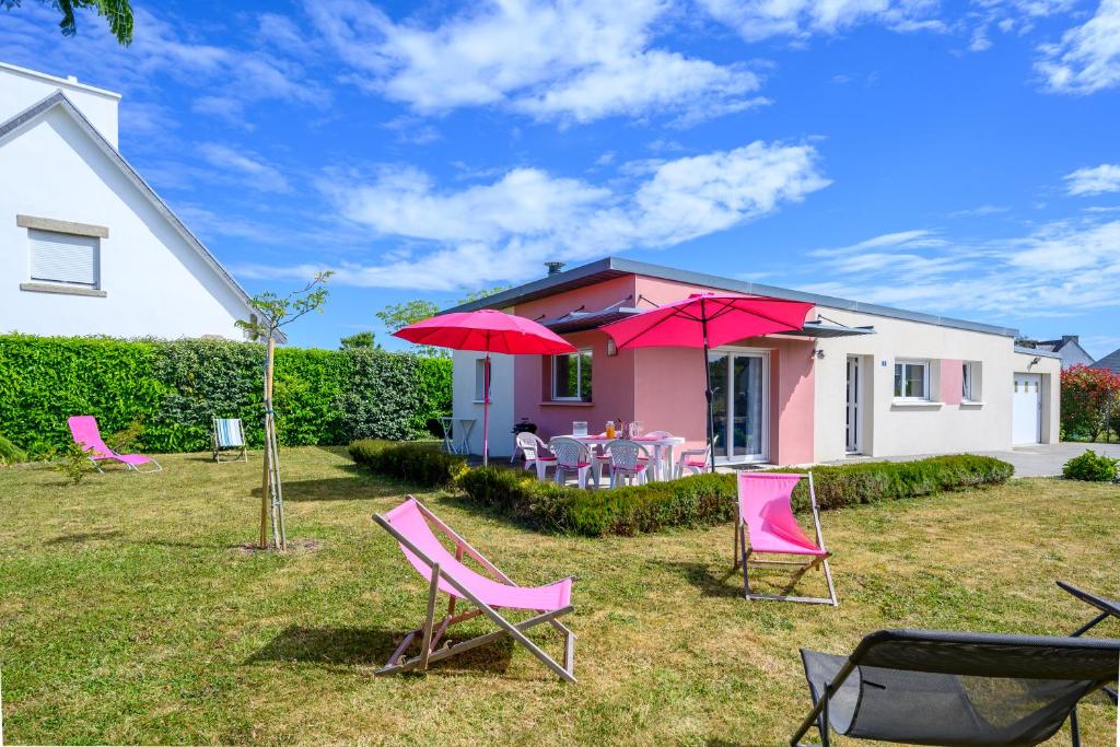 a house with pink chairs and umbrellas in the yard at AUX AQUARELLES DE LINETTE in Tréffiagat