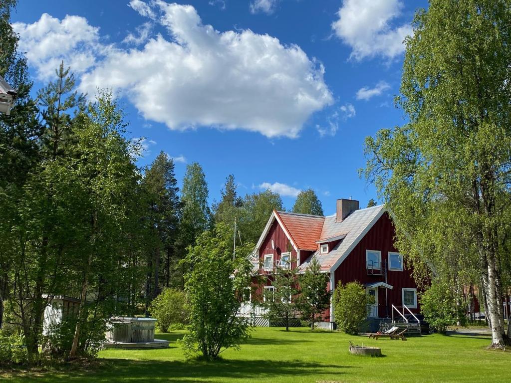 a large red house with a grass yard and trees at NaturResort Änglagård in Gargnäs