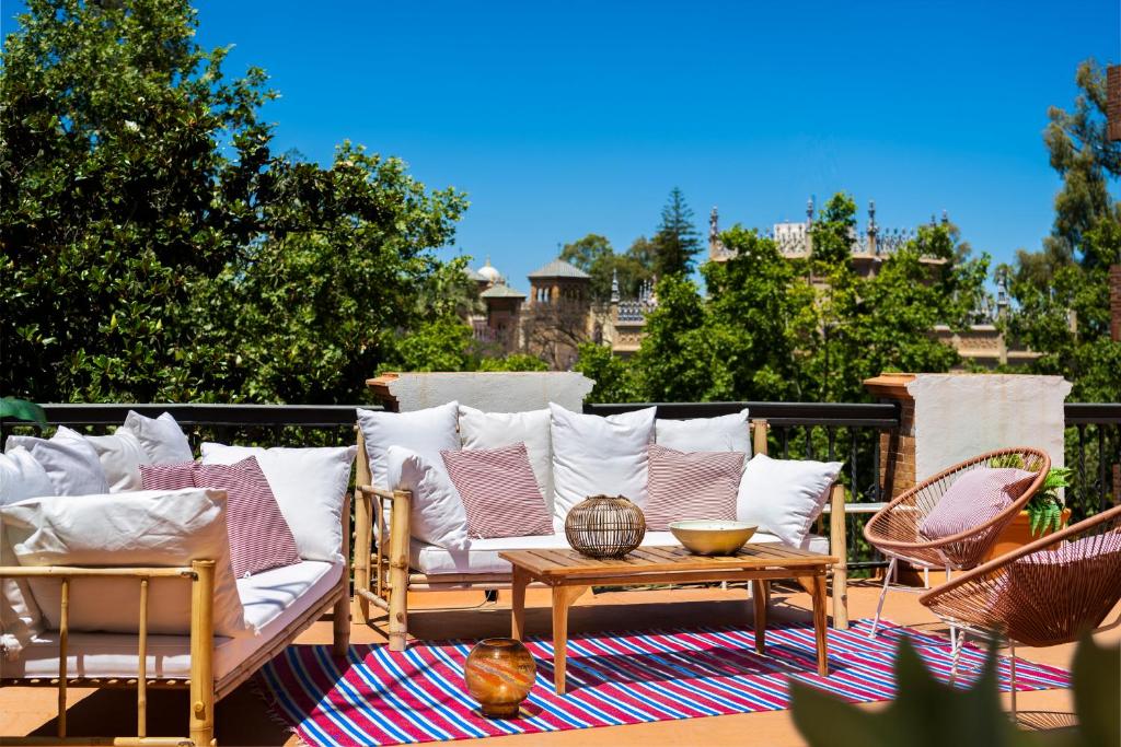 un patio con sofá, mesa y sillas en Villa Alfonso, Restored Palace House with gardens and Monuments Views en Sevilla