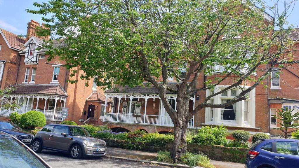 a group of houses with cars parked in front of a tree at Beautiful Garden Apartment in Leafy St Leonards 5 Mins to Beach in St. Leonards