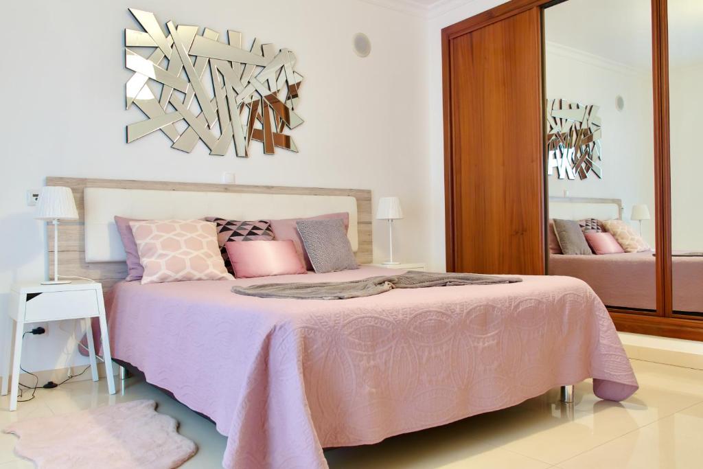 a bedroom with a pink bed with a mirror at Edificio Tomás 1 in Ferragudo