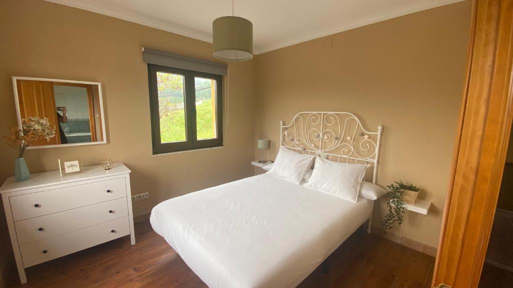 a bedroom with a white bed and a window at La Pedrosa in Fontanina