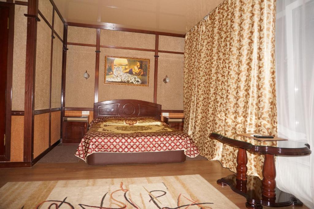 a bedroom with a bed in a room with curtains at Hotel Aura in Rostov on Don