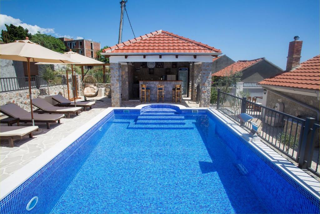 a blue swimming pool with chairs and a house at Holiday home Kristina in Krimovice