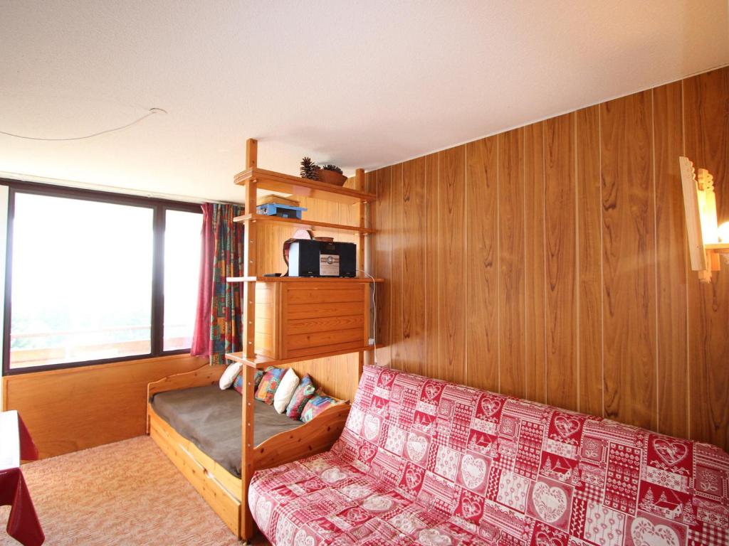 a living room with a couch and a book shelf at Studio Chamrousse, 1 pièce, 4 personnes - FR-1-549-75 in Chamrousse