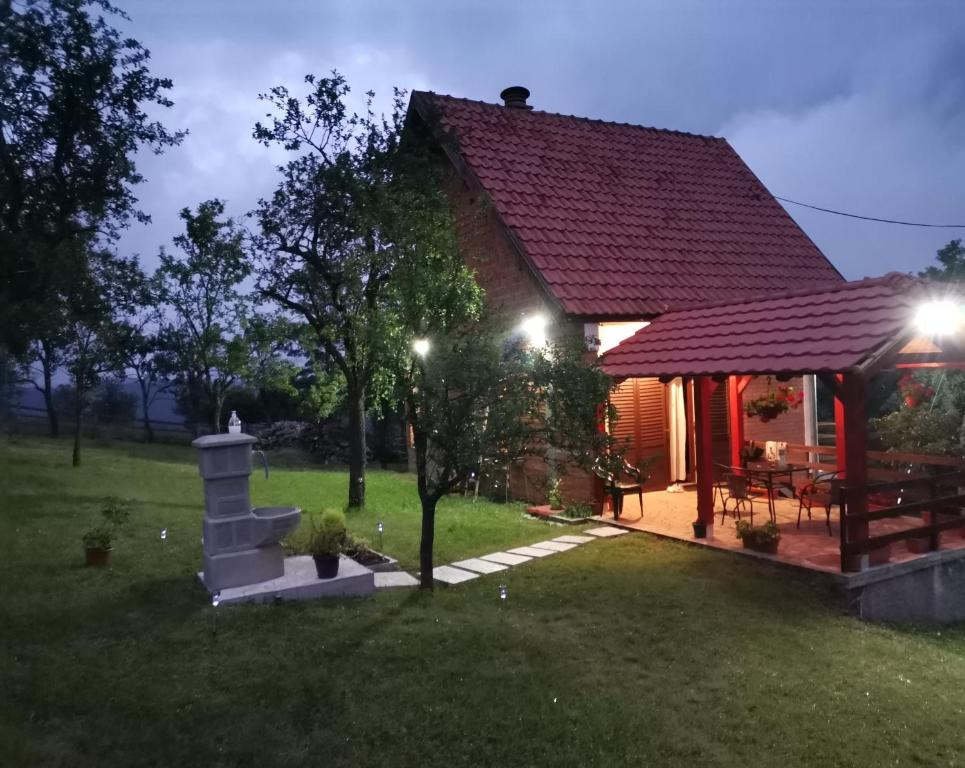 a house with a fireplace in a yard at night at Srdića Kuća in Trnava