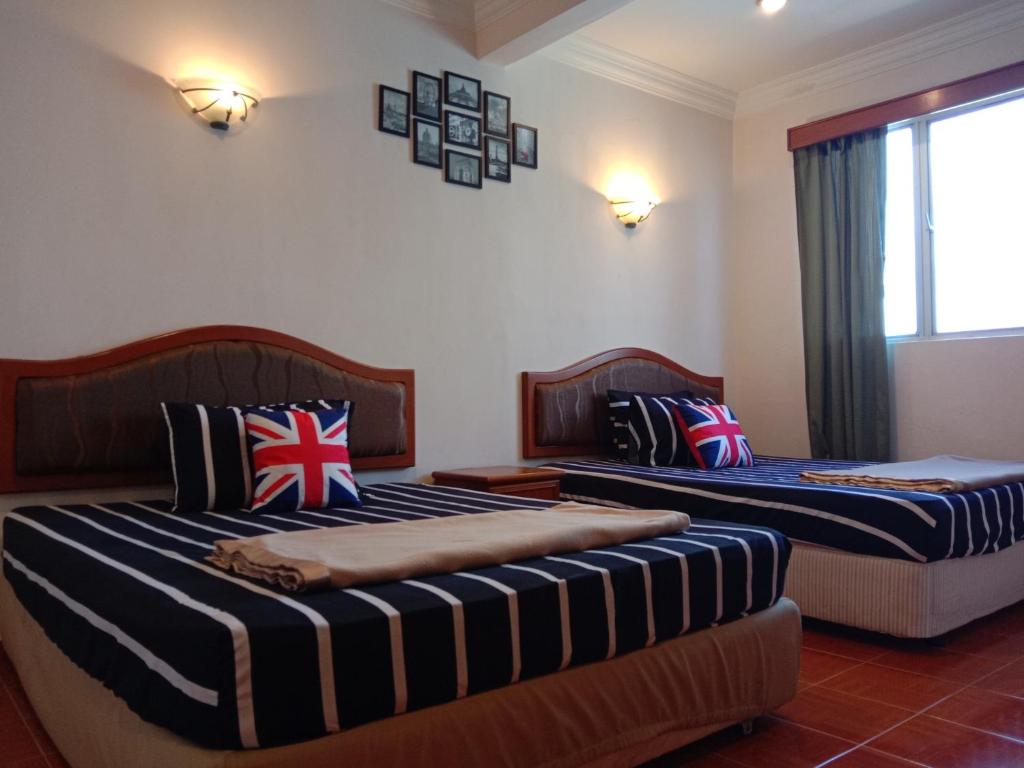 2 camas en una habitación con almohadas de bandera británica en Glory Beach Resort PriVate PentHouse en Port Dickson