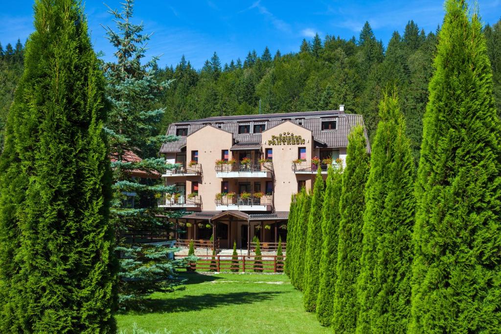 a building with trees in front of it at Pension Pantheon in Poiana Brasov