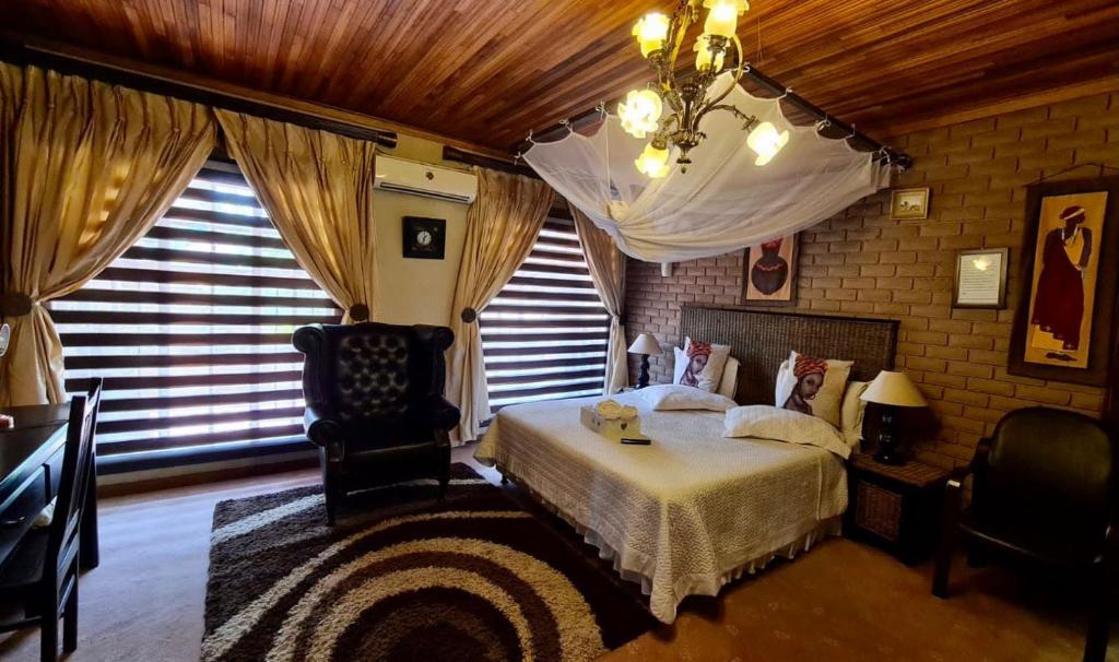 a bedroom with a bed and a chair and windows at Xisaka Guest House in Giyani