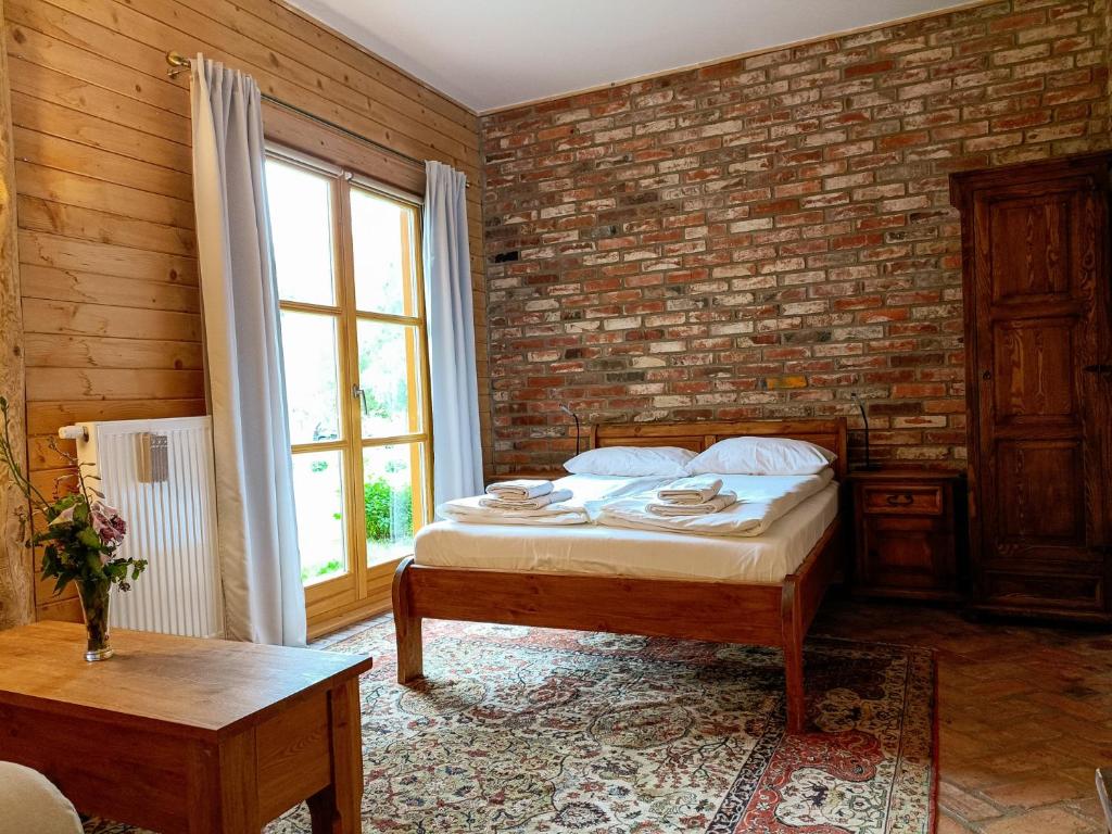 ein Schlafzimmer mit einem Bett und einer Ziegelwand in der Unterkunft Ułańska Zagroda in Człopa