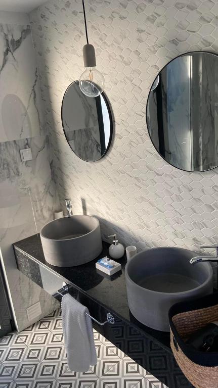 a bathroom with two sinks and two mirrors on the wall at Zambujal Suites in Sesimbra