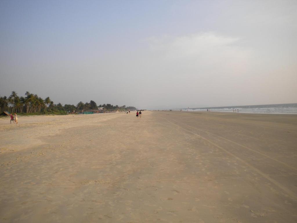 a sandy beach with people walking on it at Lotus Benaulim - Beach Apartment in Benaulim