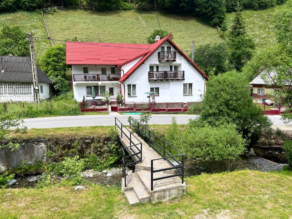 a white house with a red roof and a staircase at Căsuța de lângă pădure in Moieciu de Sus