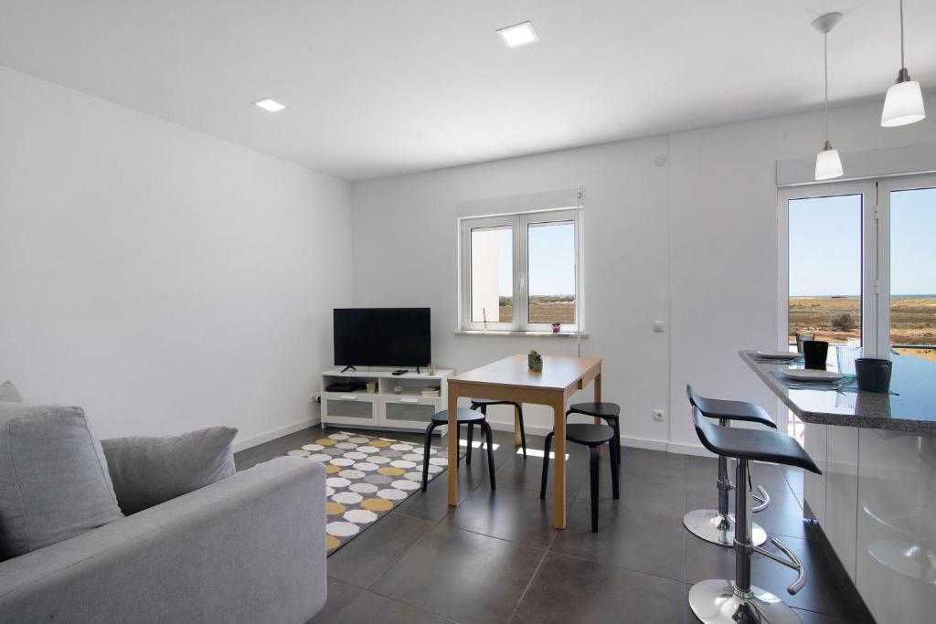 a living room with a couch and a table with chairs at Sunshine Apartment in Armação de Pêra