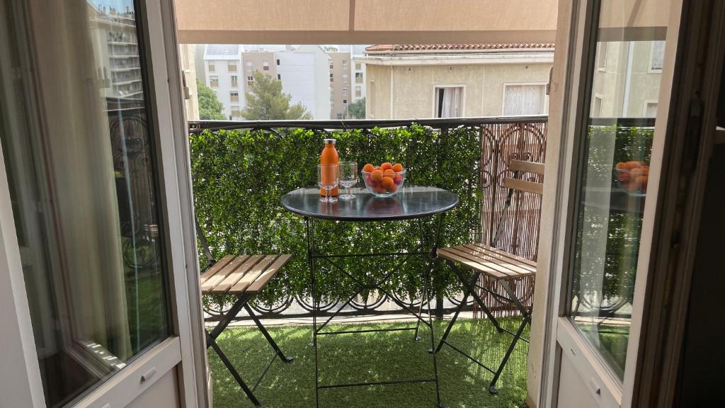 a balcony with a table and two chairs and a table with oranges at Appartement mignon calme douillet ascenseur clim étage élevé proche parking et toutes commodités au coeur du Toulon historique in Toulon