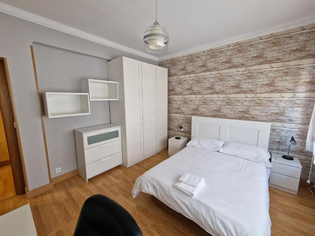 1 dormitorio con cama blanca y pared de madera en Apartamento ideal Florida, en Vitoria-Gasteiz