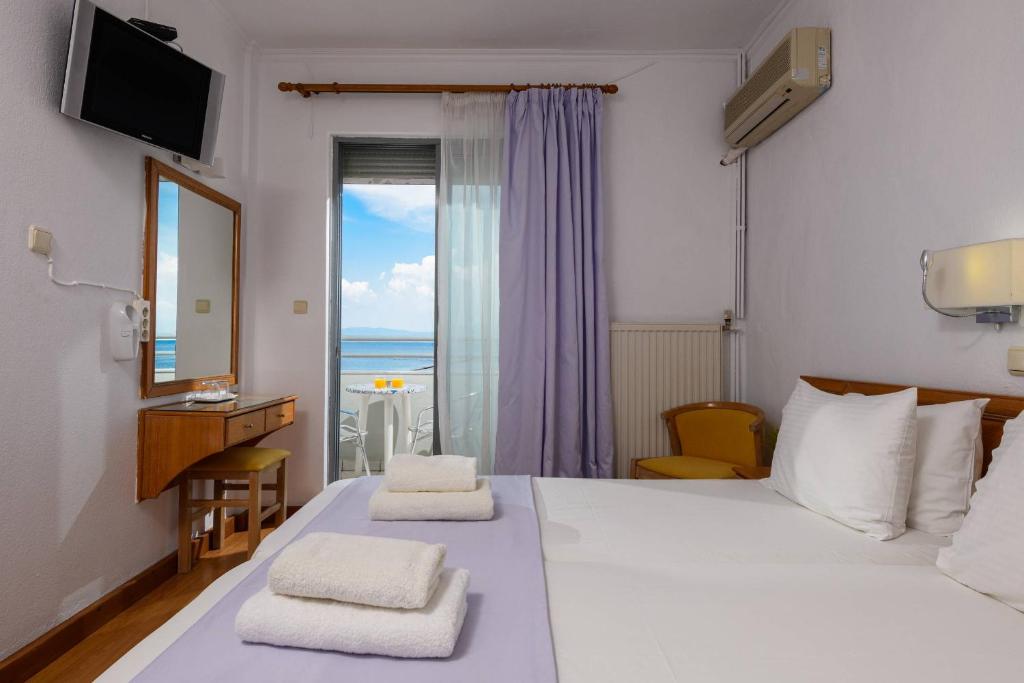 a bedroom with a bed with a view of the ocean at POSSIDON HOTEL in Limenas