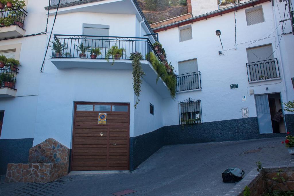 カソルラにあるCasa Rural José Maríaの茶色のドアとバルコニーが備わる白い建物