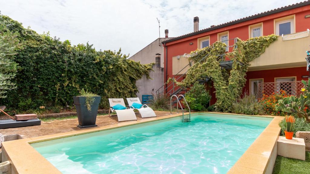 a swimming pool with chairs and a house at Spapparra B&B in Càbras