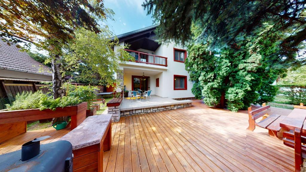 una terraza de madera con bancos y una casa en Katalin ház, en Balatonfüred