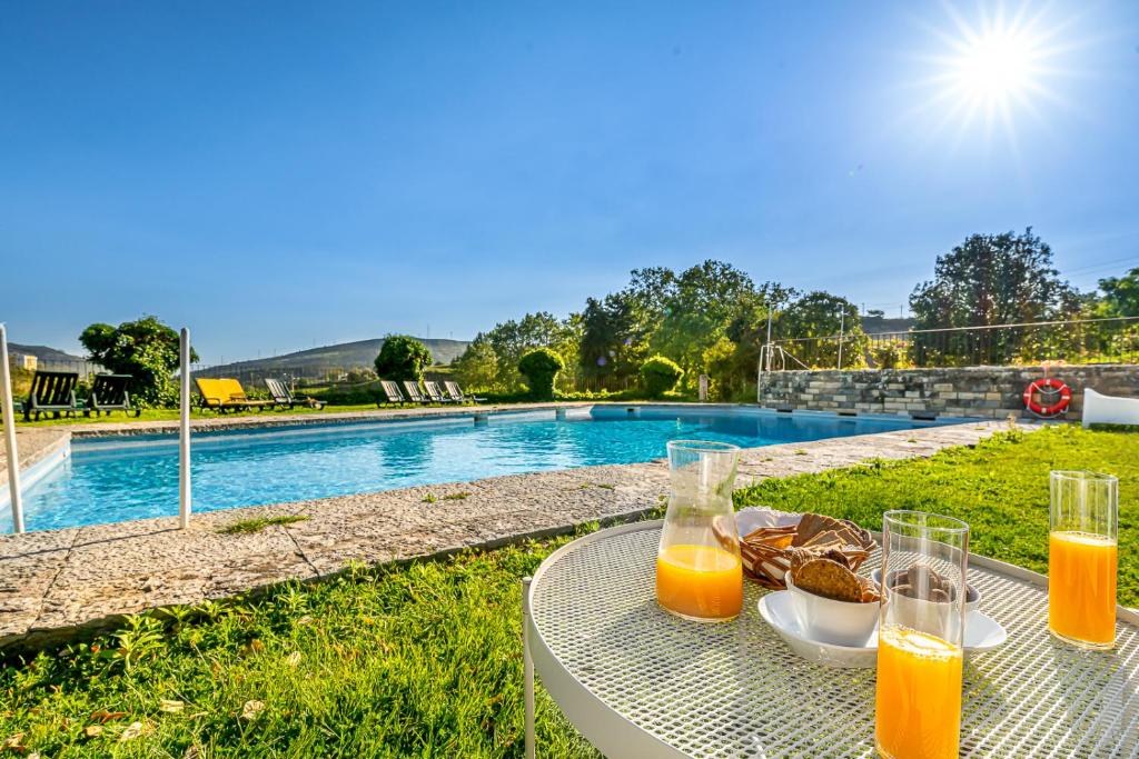 uma mesa com dois copos de sumo de laranja ao lado de uma piscina em Quinta do Boição em Lisboa