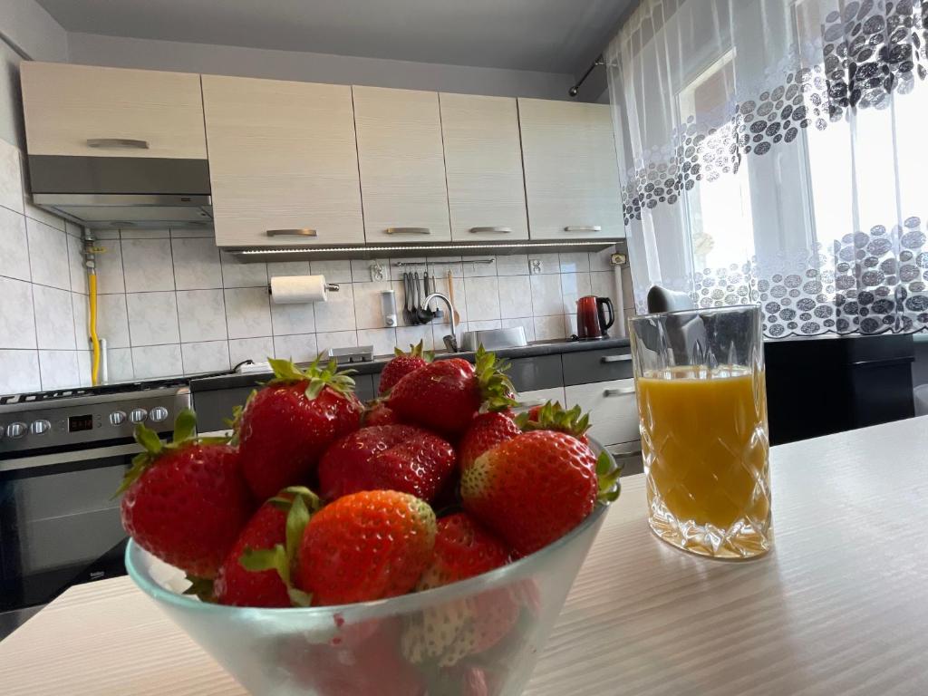 un tazón de fresas en una mesa junto a un vaso de zumo de naranja en Apartament Regina, en Ustka