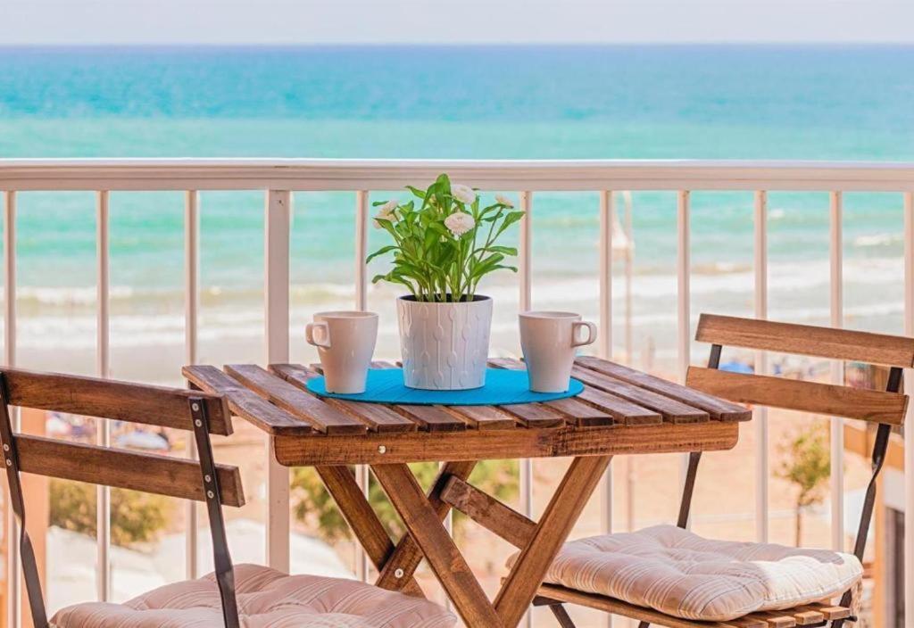 a wooden table with a potted plant on a balcony at Seaview modern beach apartment in Guardamar del Segura