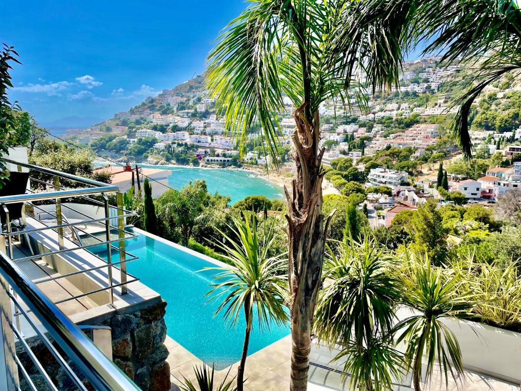 a villa with a swimming pool and a palm tree at CASTELL BLAU in Roses