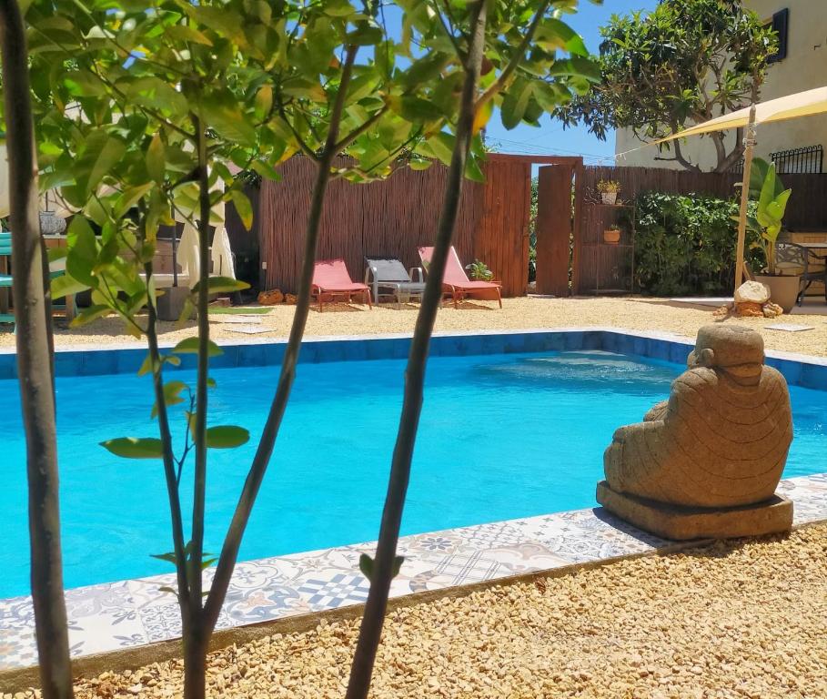 une piscine avec une statue en pierre à côté d'un arbre dans l'établissement Casa Francesca Altea piscina y aparcamiento privado, à Altea