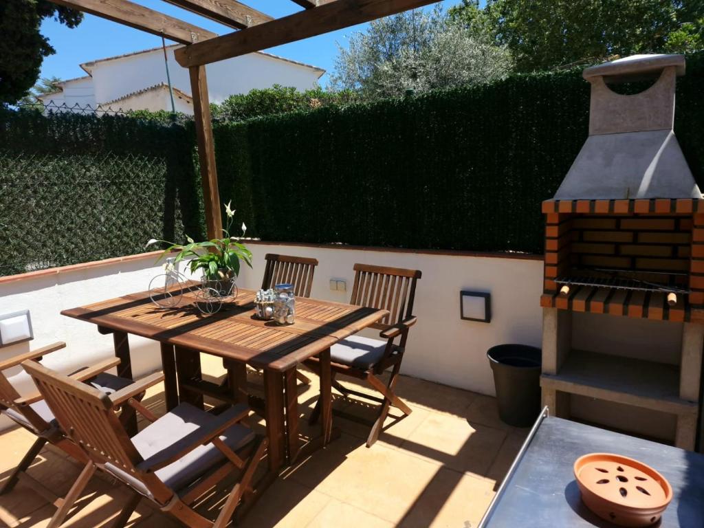 un patio con mesa de madera, sillas y parrilla en Casa Bella Castell d Aro, en Castillo de Aro