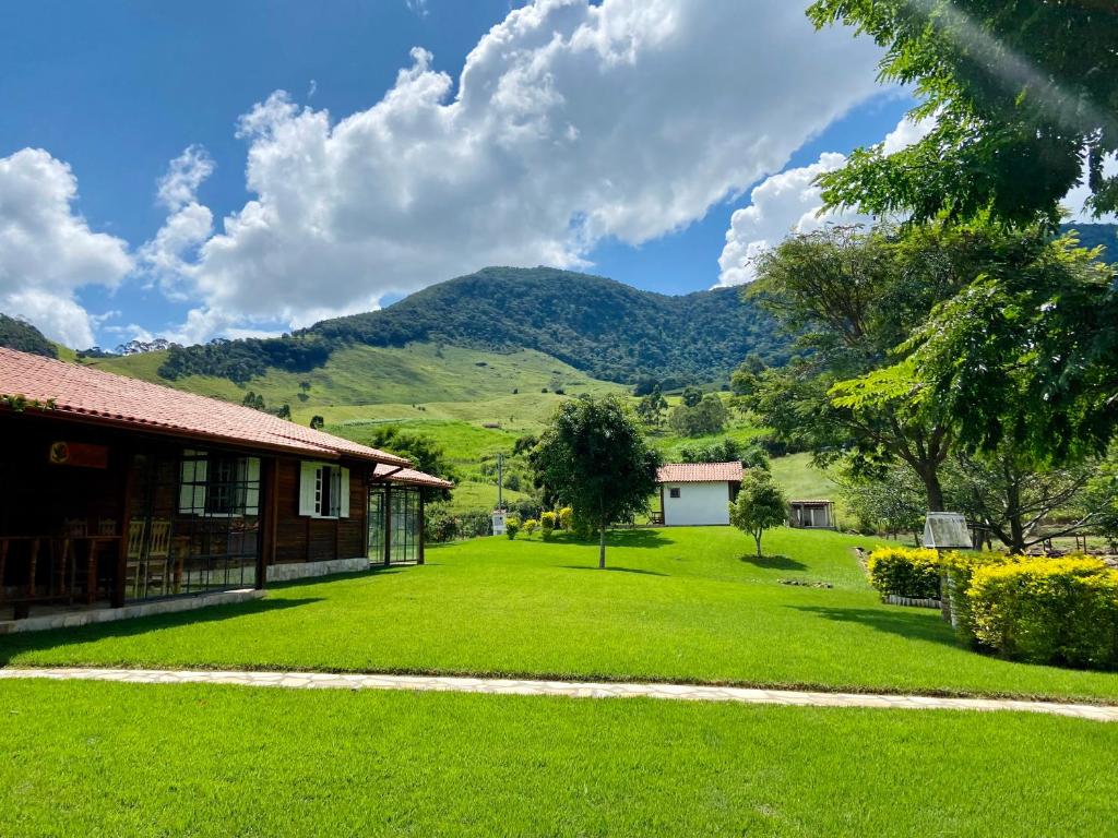 a yard with a house and mountains in the background at Quinta do Papagaio in Pouso Alto